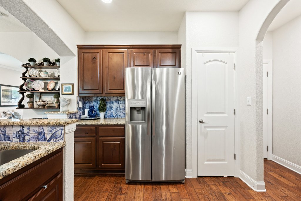 6708 Menchaca Road, Unit 2 Austin, TX 78745 - Photo 10 of 30 Kitchen featuring a stainless steel side-by-side refrigerator, wood-finish flooring, custom wood cabinetry, granite countertops, and decorative tile backsplash