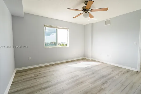an empty room with a window and a ceiling fan