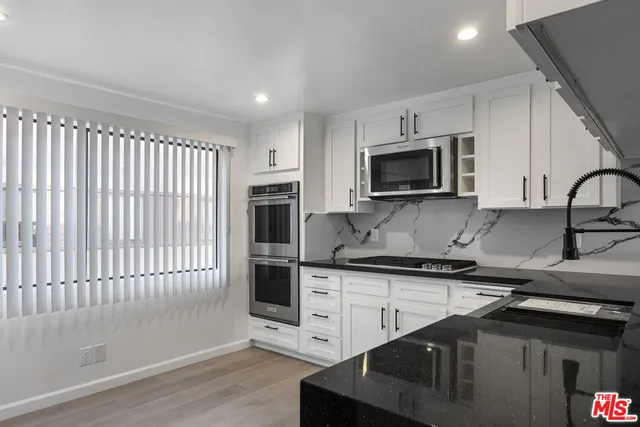 a kitchen with stainless steel appliances kitchen island granite countertop a stove a sink and a microwave