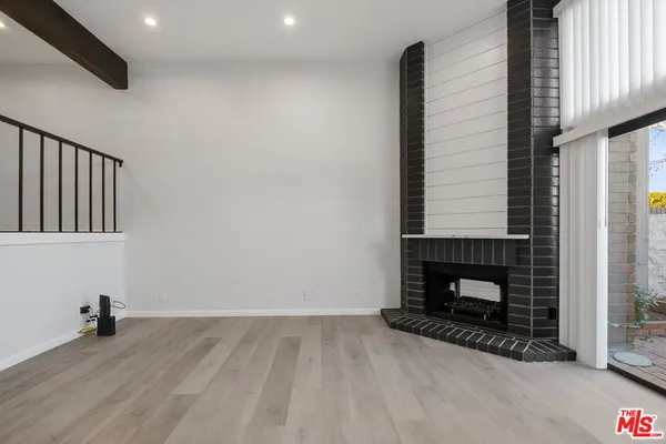 a view of an empty room with wooden floor and a fireplace