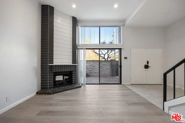 an empty room with wooden floor fireplace and windows