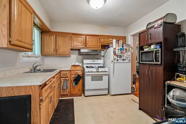 a kitchen with stainless steel appliances granite countertop a stove top oven a sink and a refrigerator