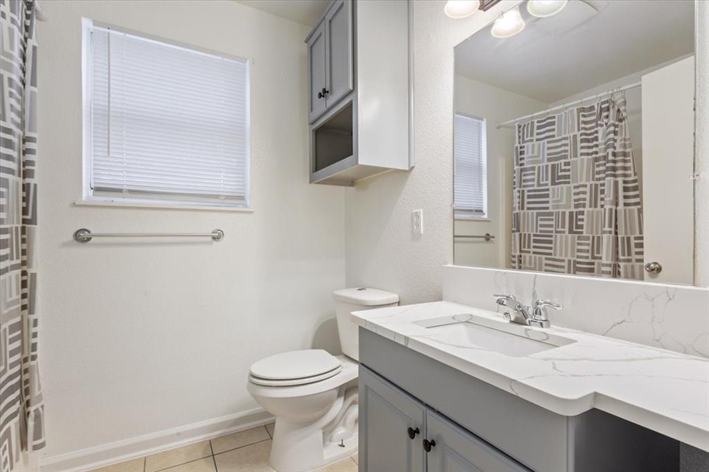 1120 Holt Avenue Waco, TX 76706 - Photo 16 of 25 a bathroom with a granite countertop sink a toilet and a mirror