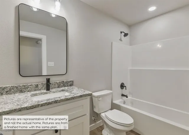 a bathroom with a granite countertop toilet sink and mirror