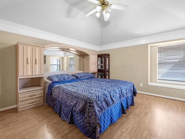 a spacious bedroom with a large bed a chandelier and windows