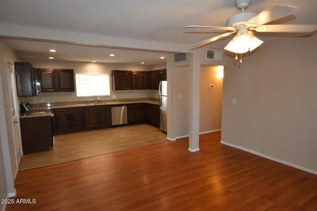 a large kitchen with wooden floor and stainless steel appliances