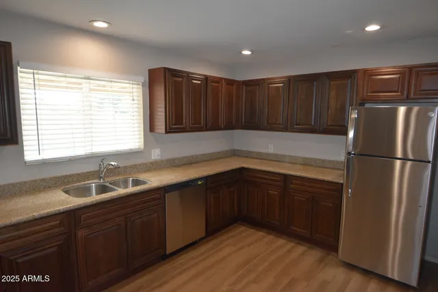 a kitchen with granite countertop stainless steel appliances a refrigerator sink and cabinets