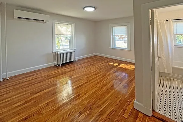 an empty room with wooden floor and windows