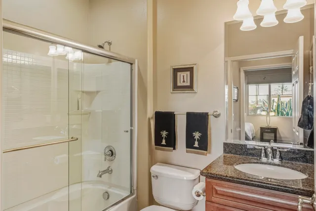 a bathroom with a granite countertop sink a toilet a mirror and shower