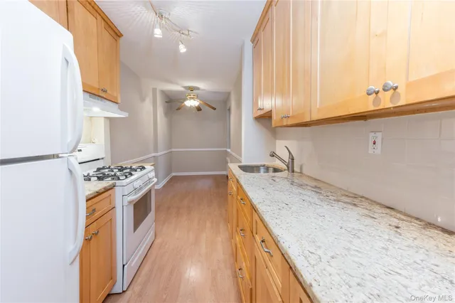 a view of a kitchen with a sink and dishwasher a stove top oven with wooden floor