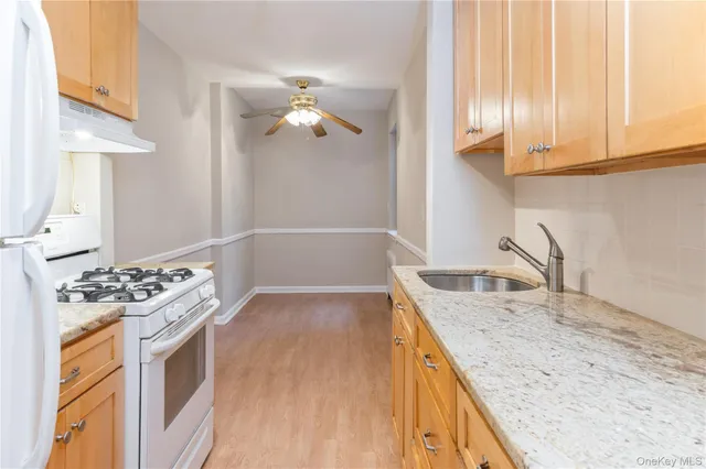 a kitchen with granite countertop a sink a stove and cabinets