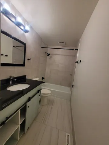 a bathroom with a granite countertop sink mirror vanity and toilet