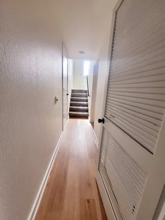 a view of a hallway with wooden floor and staircase
