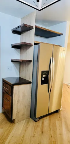 a view of a refrigerator in kitchen and an empty room