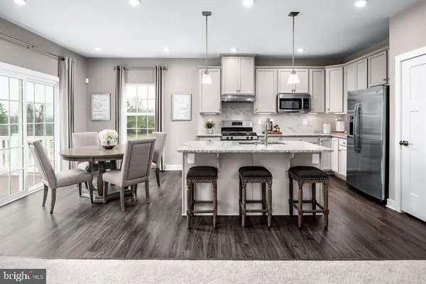 a open kitchen with stainless steel appliances granite countertop a dining table chairs refrigerator microwave and cabinets