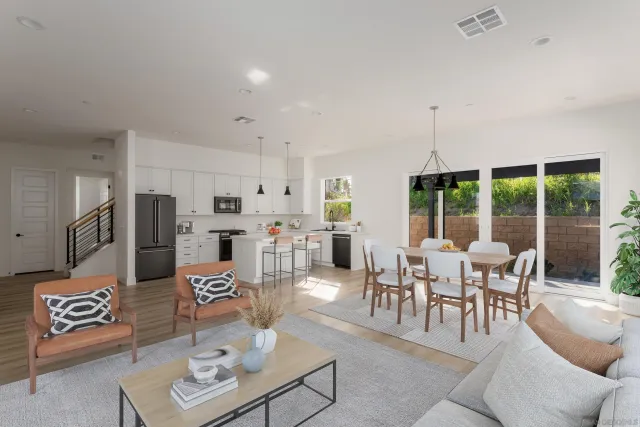a view of a dining room and livingroom with furniture wooden floor a rug and a chandelier