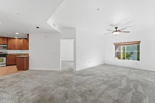 an empty room with a chandelier fan and windows