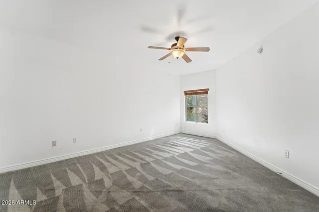 an empty room with a window and a ceiling fan