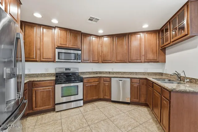 a kitchen with stainless steel appliances granite countertop wooden cabinets a stove top oven a sink and dishwasher