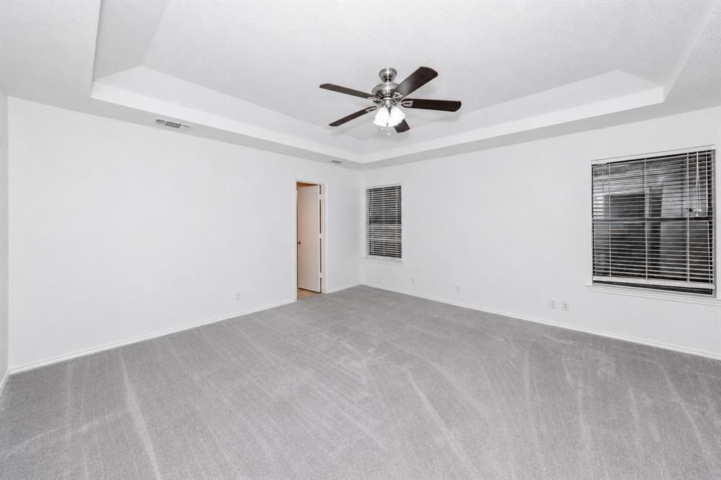 1001 Rosebud Drive Azle, TX 76020 - Photo 25 of 36 Spacious room featuring a tray ceiling with ceiling fan, light gray carpet, and multiple windows with blinds