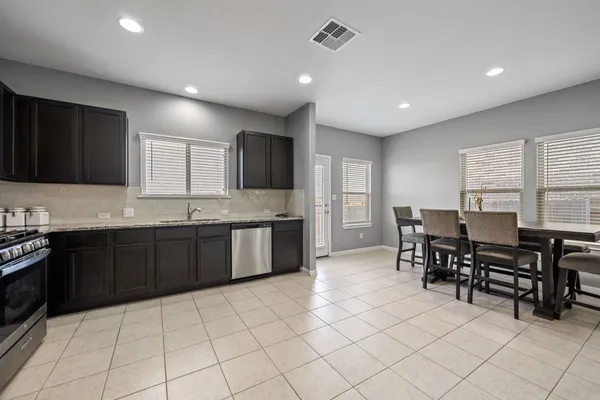 a kitchen with stainless steel appliances granite countertop a stove a sink a dining table and chairs