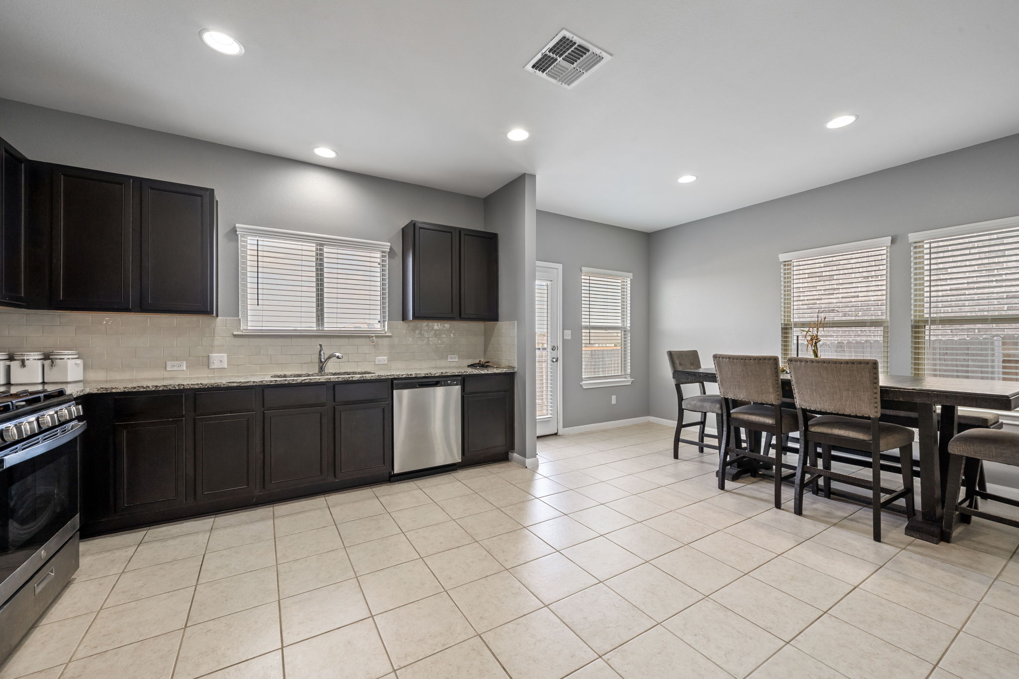 436 Spinnaker Loop Kyle, TX 78640 - Photo 3 of 14 a kitchen with stainless steel appliances granite countertop a stove a sink a dining table and chairs