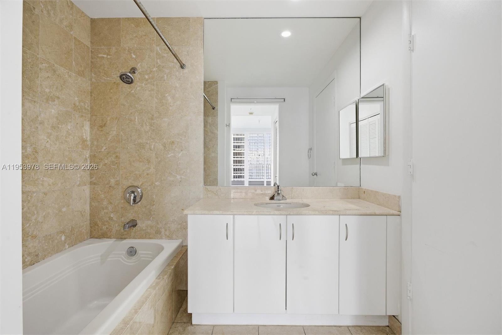 801 Brickell Key Boulevard, Unit 1404 Miami, FL 33131 - Photo 14 of 44 a bathroom with a granite countertop sink a mirror a bathtub and shower