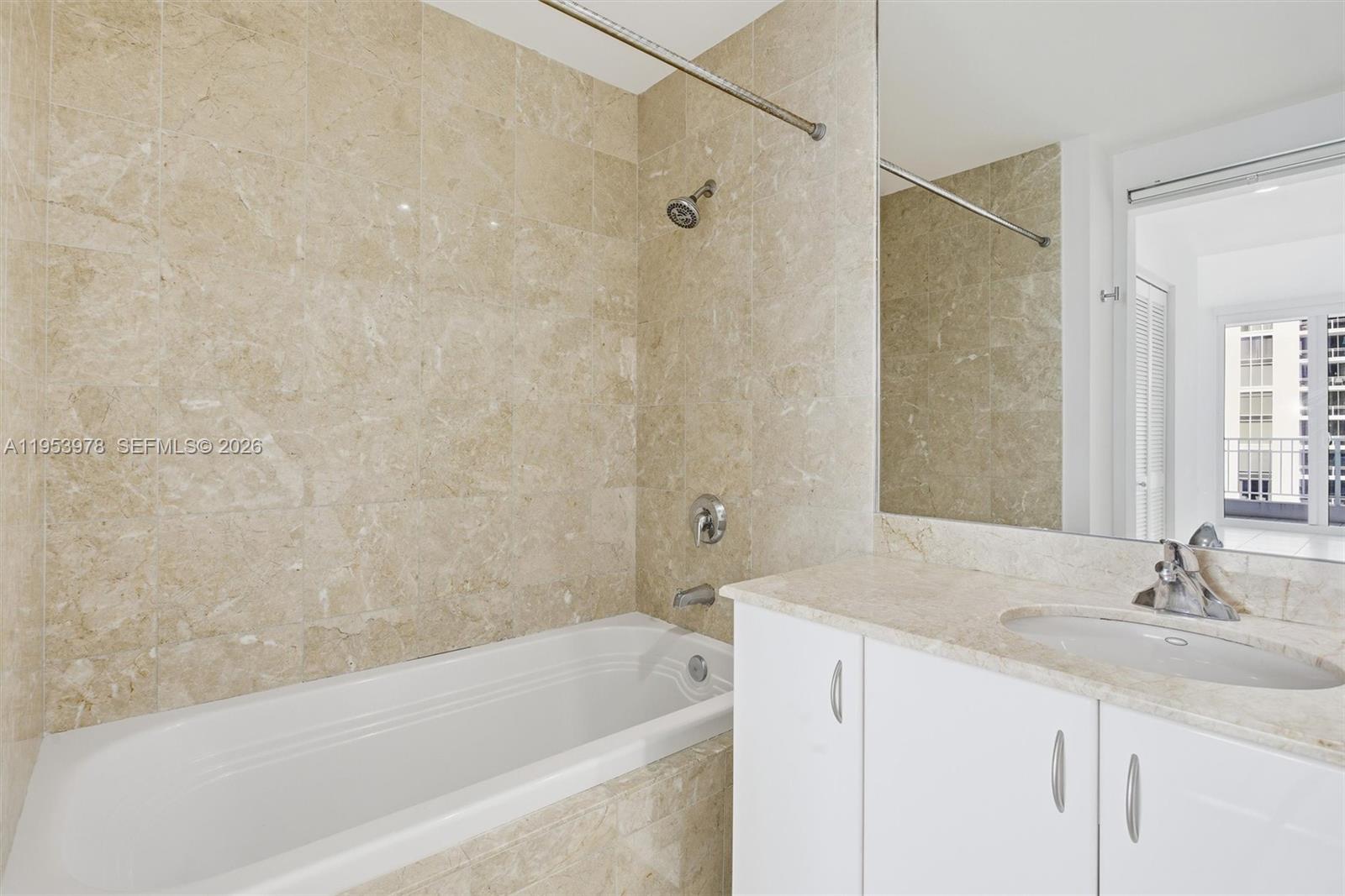 801 Brickell Key Boulevard, Unit 1404 Miami, FL 33131 - Photo 15 of 44 a bathroom with a granite countertop sink a mirror bathtub and shower