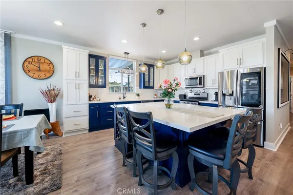 a kitchen with stainless steel appliances granite countertop a stove top oven a sink dishwasher a dining table and chairs with wooden floor