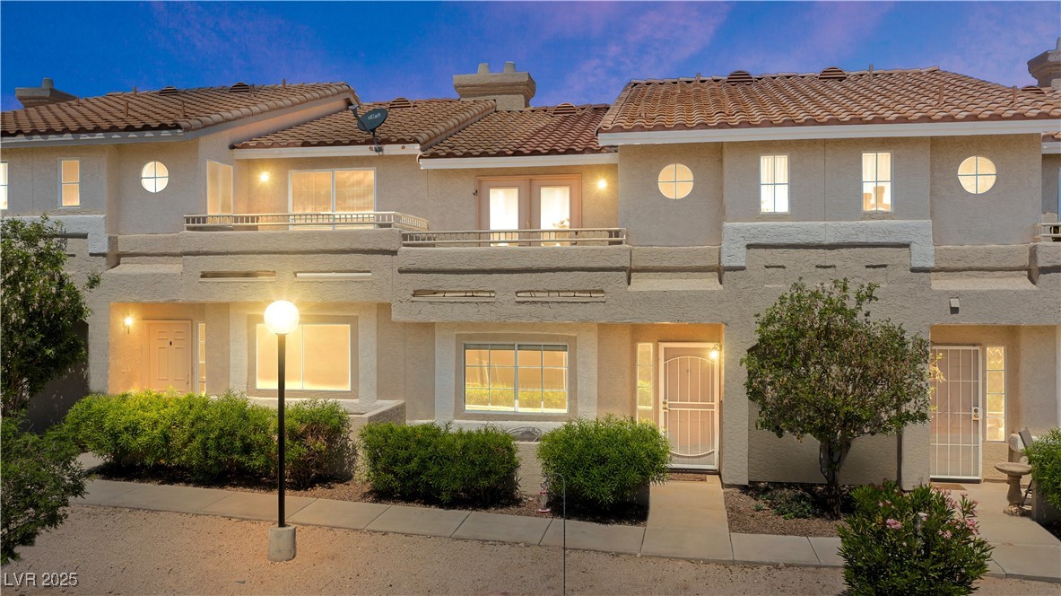 Back of house with a tiled roof, a chimney, stucco siding, and a balcony