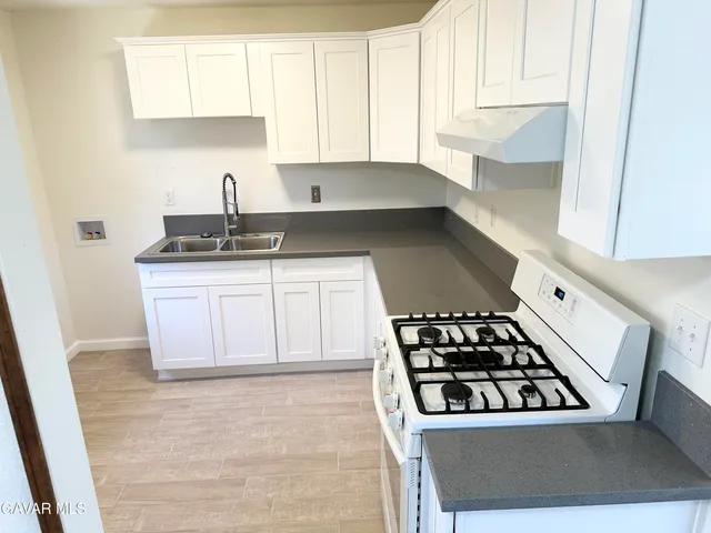 a kitchen with granite countertop a sink stove and cabinets