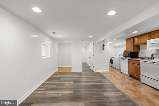 a large white kitchen with kitchen island a sink stainless steel appliances and cabinets