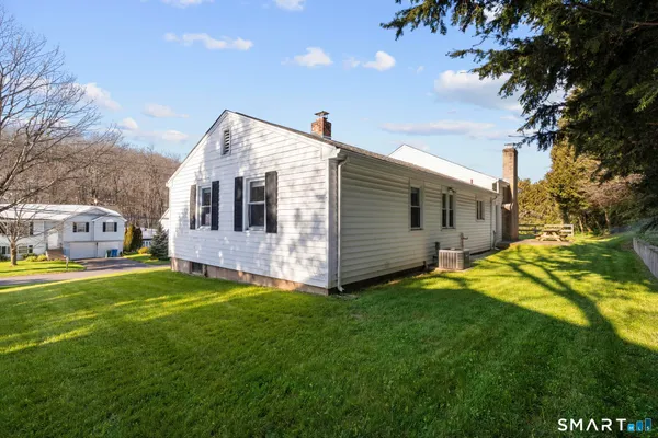 a front view of house with yard and trees in the background