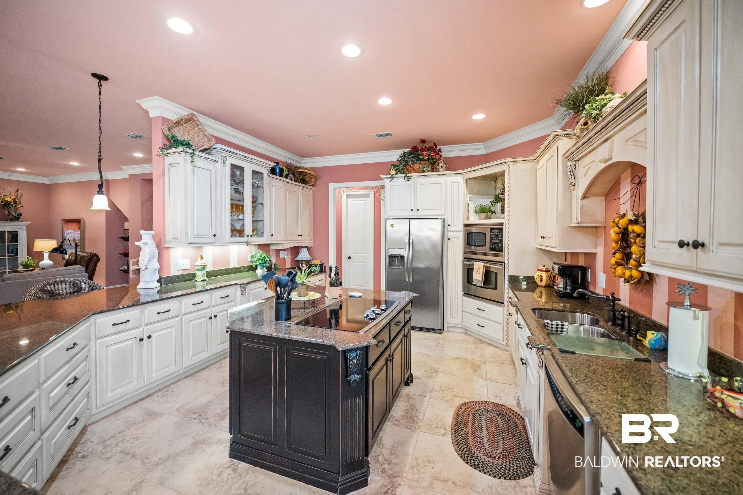 404 Peninsula Boulevard Gulf Shores, AL 36542 - Photo 7 of 51 Kitchen featuring crown molding, stainless steel appliances, dark stone countertops, glass insert cabinets, and hanging light fixtures