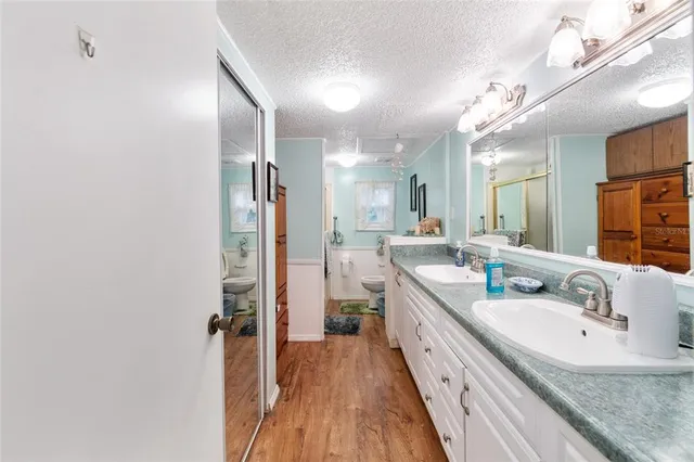 a spacious bathroom with a granite countertop sink a toilet a mirror and shower