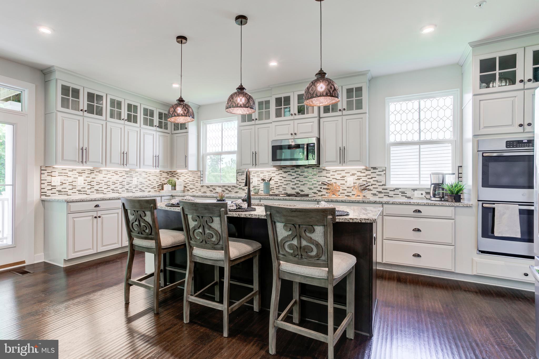 2346 Sweet Pepperbrush Loop Dumfries, VA 22026 - Photo 24 of 84 a kitchen with stainless steel appliances kitchen island granite countertop a wooden floor and white cabinets