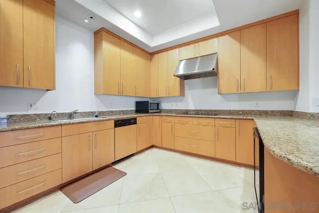 a kitchen with granite countertop a sink a stove and cabinets