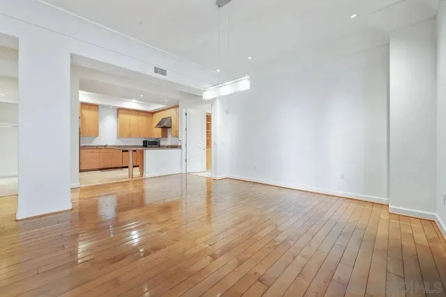 a view of a kitchen and an empty room with wooden floor