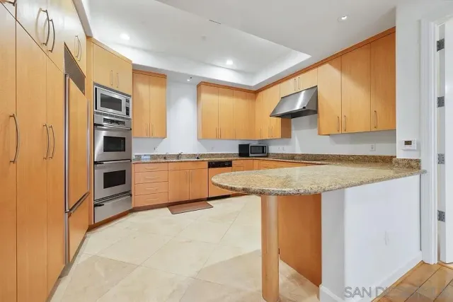 a kitchen with stainless steel appliances granite countertop a stove a sink and a refrigerator with wooden floor