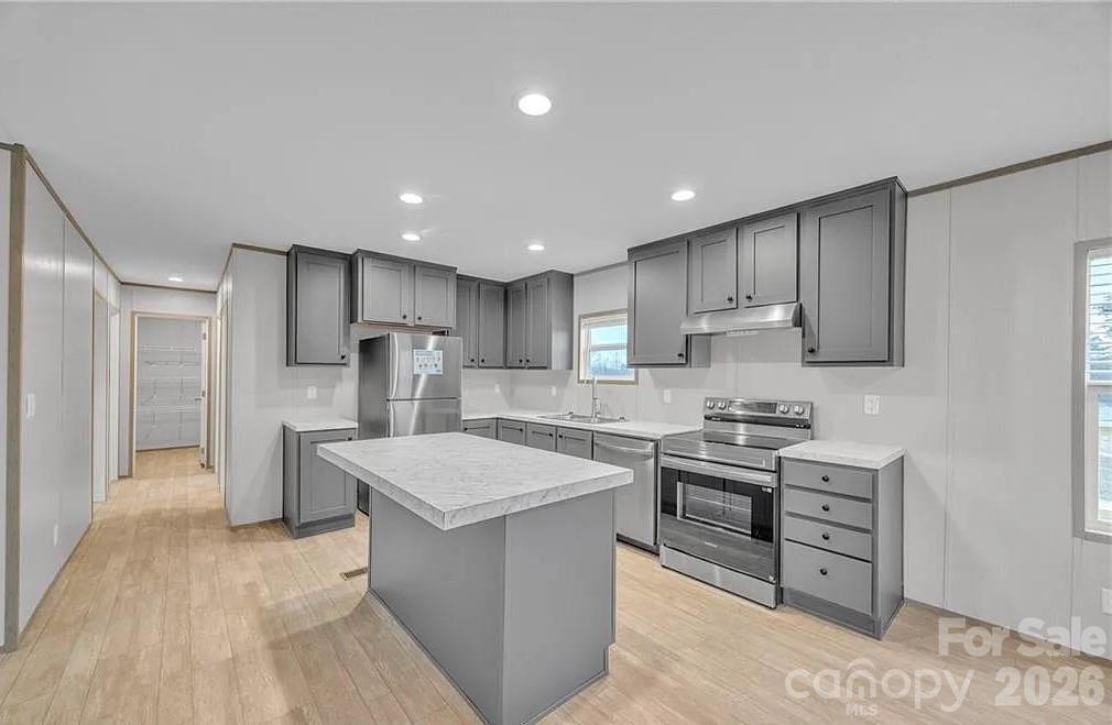 4935 Rhoney Road Connelly Springs, NC 28612 - Photo 11 of 36 a kitchen with stainless steel appliances granite countertop a sink stove oven a refrigerator with white cabinets and wooden floor