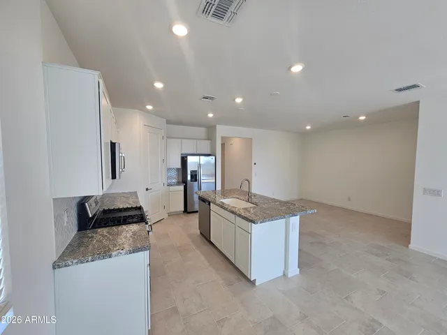 a large kitchen with stainless steel appliances granite countertop a large counter top a stove and a refrigerator