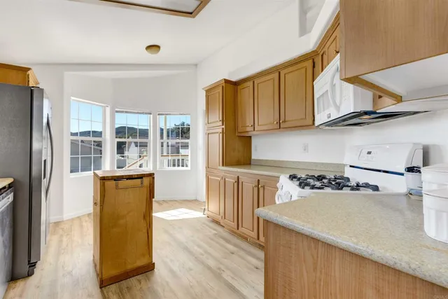 a kitchen with stainless steel appliances kitchen island granite countertop a refrigerator and a stove top oven