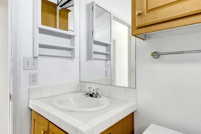 a bathroom with a granite countertop bathtub shower sink vanity and toilet