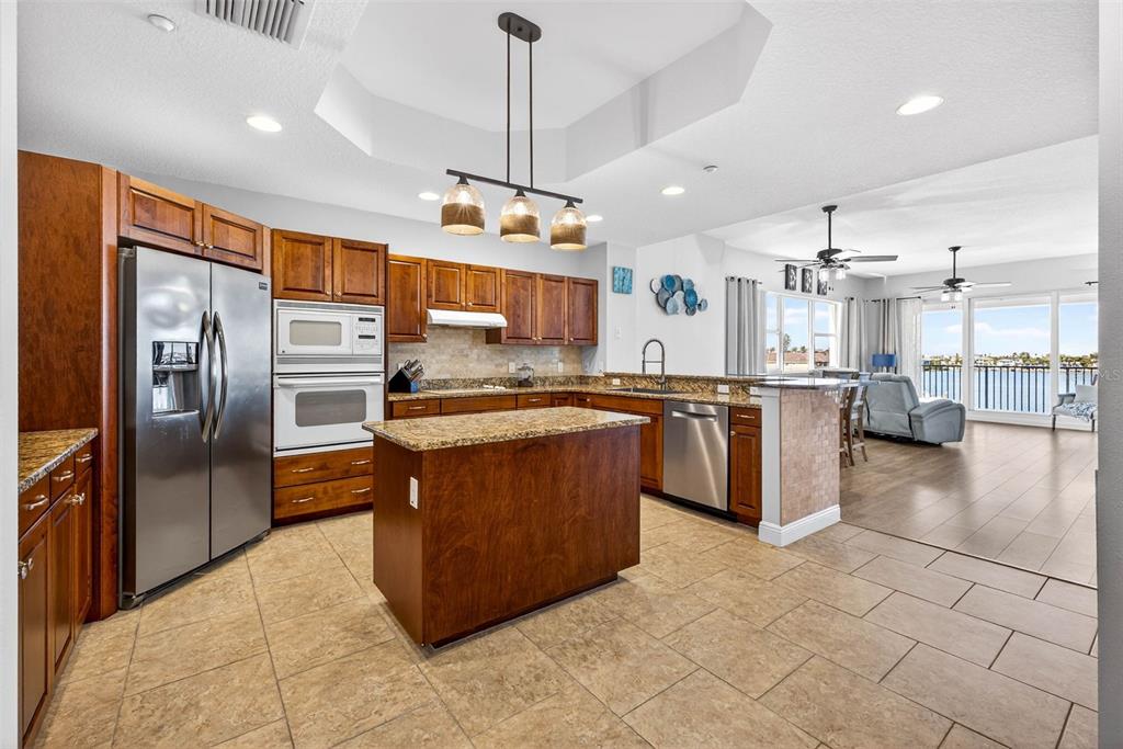 17717 Gulf Boulevard, Unit 401 Redington Shores, FL 33708 - Photo 6 of 66 a kitchen with stainless steel appliances granite countertop a refrigerator a stove and a sink with cabinets