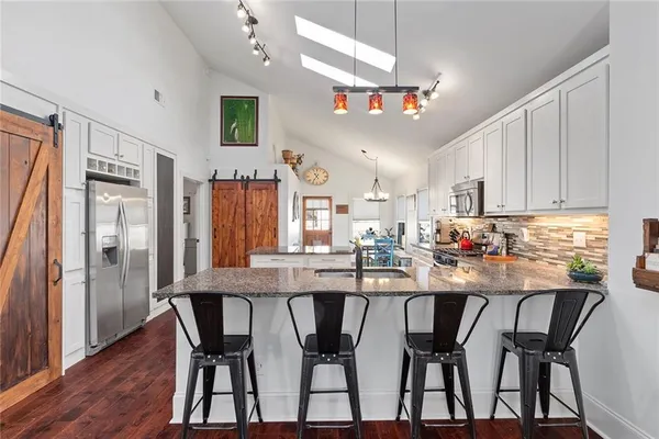 a kitchen with stainless steel appliances a dining table chairs refrigerator and cabinets