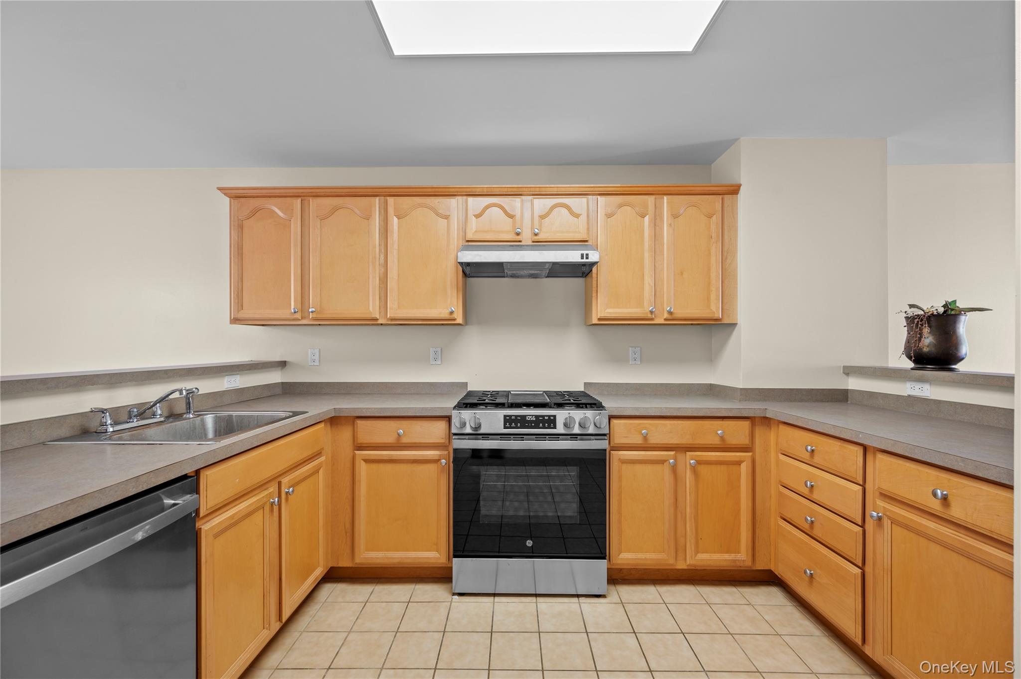 19 Putters Way, Unit 9 Middletown, NY 10940 - Photo 5 of 22 Kitchen with stainless steel appliances, light tile patterned floors, under cabinet range hood, light brown cabinets, and a skylight