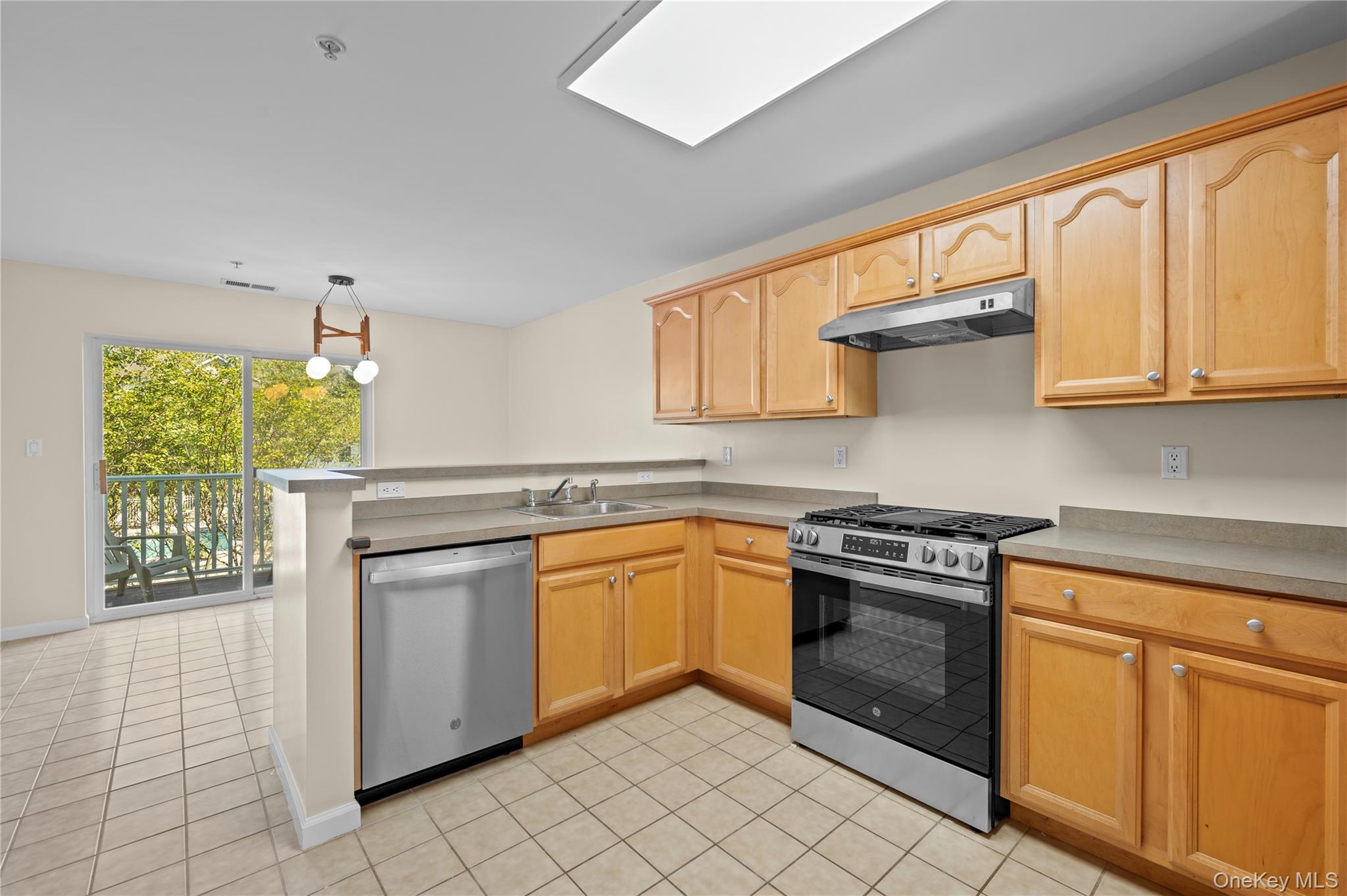 19 Putters Way, Unit 9 Middletown, NY 10940 - Photo 6 of 22 Kitchen with a peninsula, appliances with stainless steel finishes, under cabinet range hood, light tile patterned flooring, and hanging light fixtures