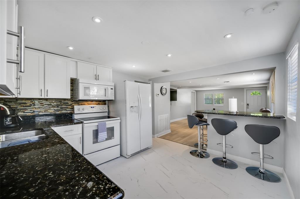 1601 Palm Way Largo, FL 33771 - Photo 10 of 25 a kitchen with stainless steel appliances granite countertop a stove a sink a refrigerator and white cabinets