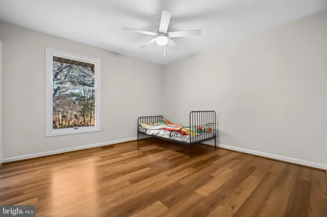 a view of empty room with wooden floor and fan