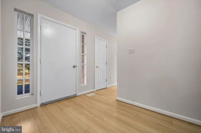 an empty room with wooden floor fireplace and windows